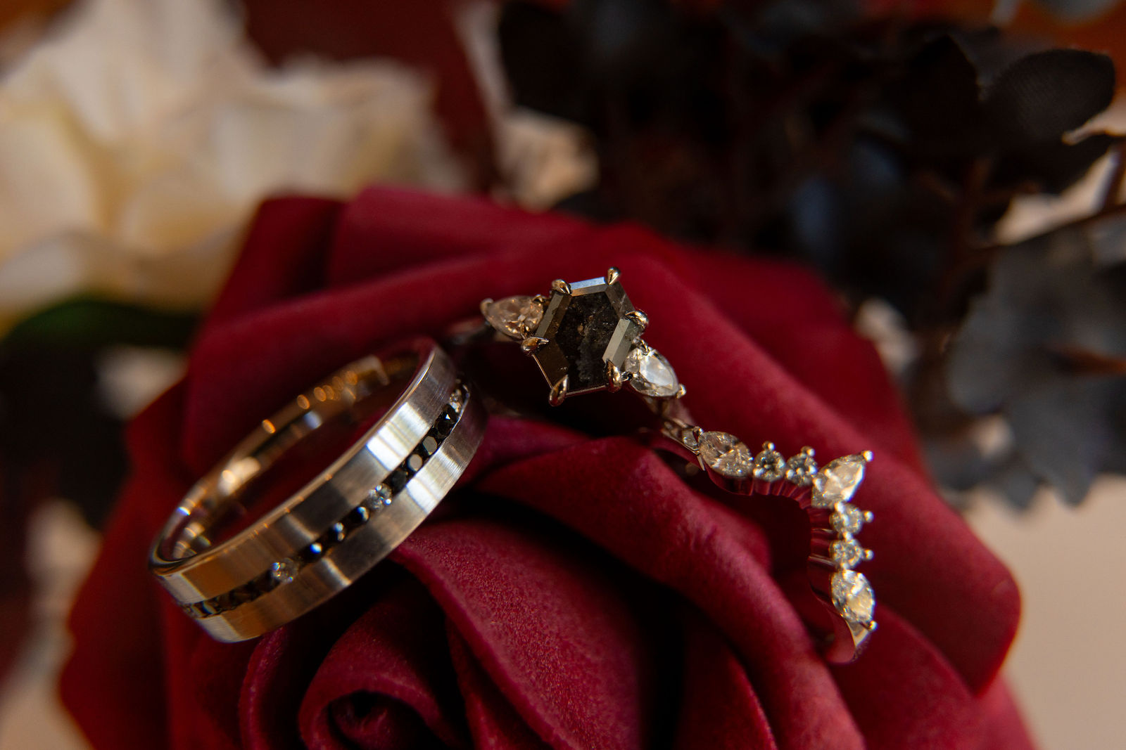 Close-up of wedding rings resting on a deep red rose, photographed by Liesl Webber